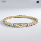 A gold tennis bracelet with a row of round-cut clear stones, displayed on a light gray background. The brand logos 'ARIA'S LARA GUTTA' and 'Sparkle' are visible in the top corners.