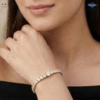 A close-up lifestyle shot of a model wearing a gold tennis bracelet adorned with sparkling clear stones. The brand logos for 'Ariane Lara' and 'Sparkles' are visible in the corners.