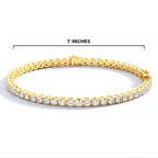 A gold tennis bracelet with clear stones, shown on a white background with a black measurement line indicating a width of 7 inches.
