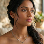 Woman wearing a delicate gold necklace with a blurred natural background