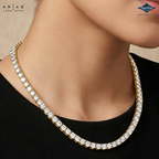A close-up of a model wearing a Lara Dutta Arias necklace. The necklace is a gold tennis-style chain paved with clear square-cut gemstones, worn over a black top.