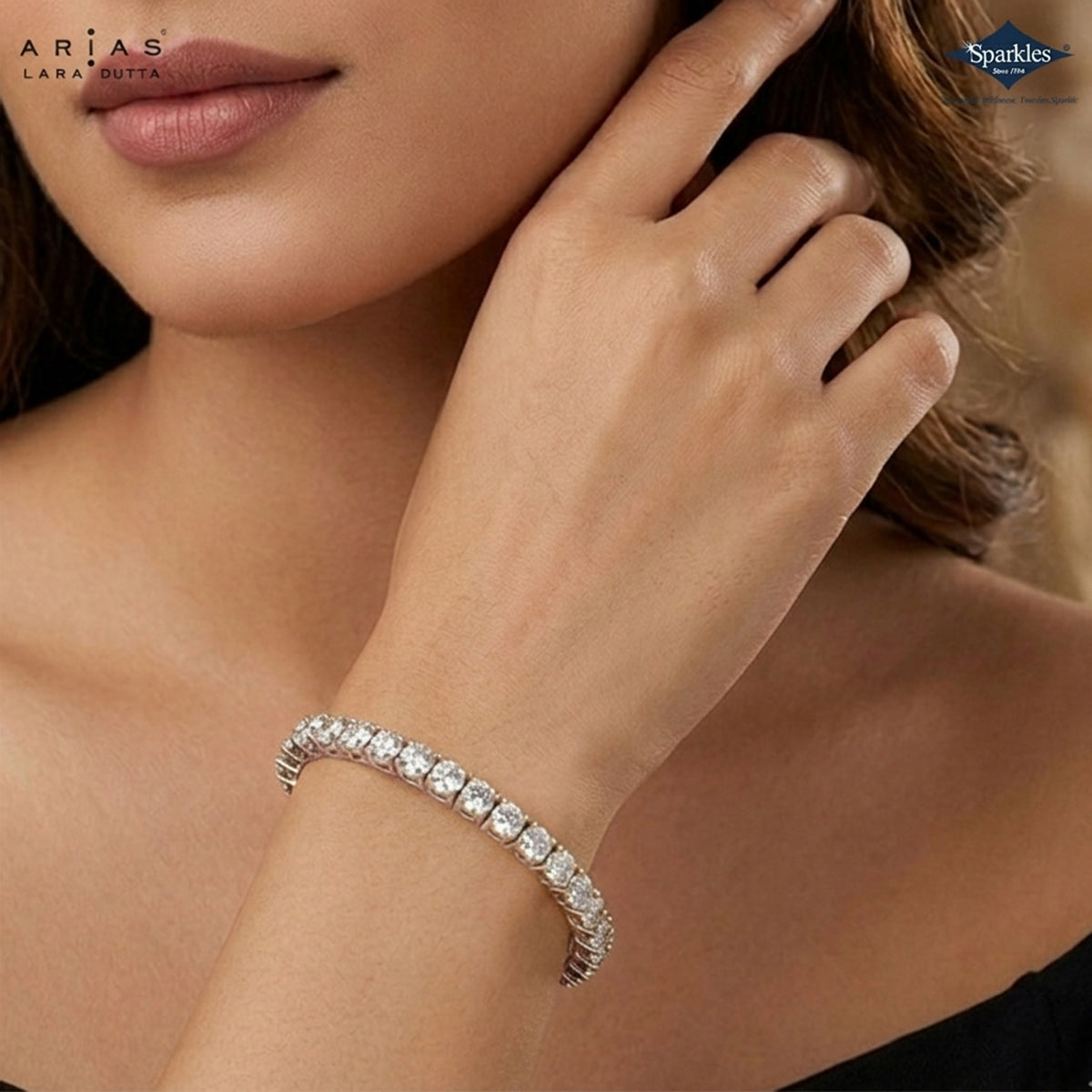 A close-up lifestyle shot of a model wearing a Lara Rita Arias sparkling tennis bracelet on her wrist. The silver-toned bracelet features a continuous line of clear round-cut gemstones.