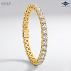 A gold tennis bracelet with clear round-cut stones, shown on a light gray gradient background. The brand logos 'Ariás Lara Dutta' and 'Sparkles' are visible in the top corners.