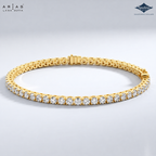 A gold tennis bracelet with a row of round-cut clear gemstones, displayed on a light gray gradient background. The brand logos 'ARIAS LARA DUTTA' and 'Sparkle' are visible in the top corners.