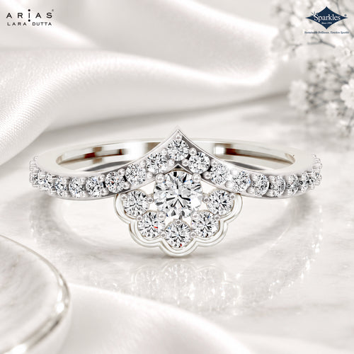 A silver-tone wedding band featuring a prominent scalloped diamond cluster centerpiece and a matching pavé band, displayed on a reflective white satin surface. The brand logos for ARIAS Lara Dutta and Sparkles are visible in the corners.