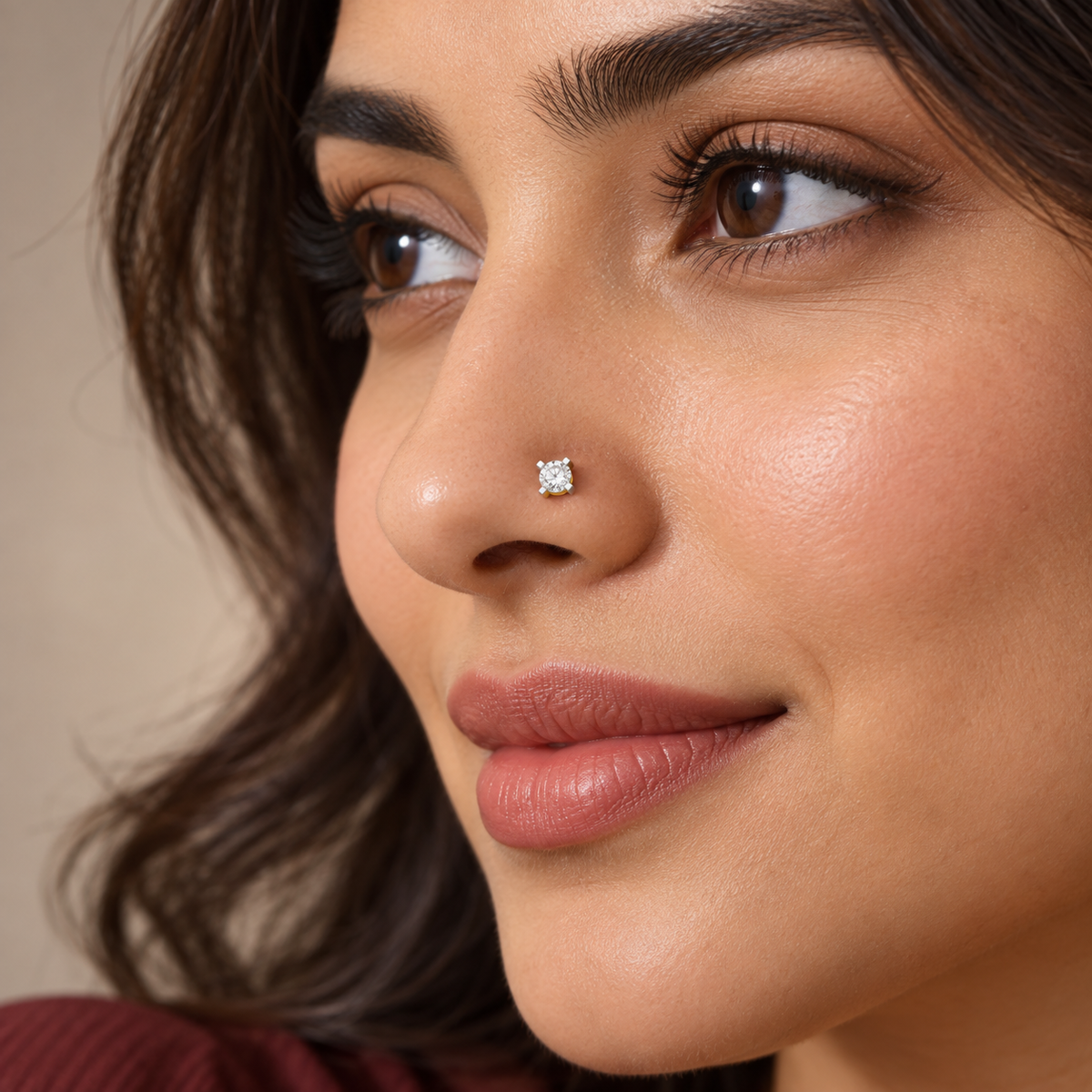 A close-up of a woman wearing a small square-cut diamond stud earring on her nose, set in a silver-tone setting.