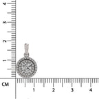 A round silver pendant with a halo of small clear stones around a central starburst design, shown next to a black ruler with centimeter markings for size reference.
