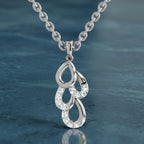 Silver necklace with a detailed pendant against a blue water background
