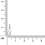 Silver pendant with a heart and diamond design next to a ruler for scale on a white background