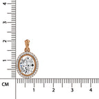 An oval pendant with a clear central gemstone surrounded by a halo of small clear stones in a rose gold setting, shown next to a centimeter ruler for scale on a white background.