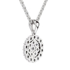 A silver pendant necklace featuring a circular, textured design with small inset circular details, suspended from a silver chain on a plain white background.