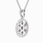 A silver-toned oval pendant necklace featuring a geometric, multi-layered design with small clear gemstones, suspended from a matching silver chain against a light gray background.