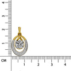 A gold and white gold oval pendant with a central round diamond, flanked by smaller diamonds, shown next to a centimeter ruler for scale on a white background.