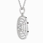A silver-toned oval pendant necklace featuring concentric halo rings and a central diamond, suspended from a matching chain against a light gray background.