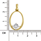 A gold oval pendant with a single clear gemstone in a prong setting, shown next to a centimeter ruler for scale on a white background.