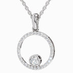A silver-toned necklace featuring an open circular pendant encrusted with small clear stones and a smaller round clear stone at the bottom, suspended from a matching chain against a light gray background.