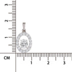 A silver oval pendant with a halo of small clear stones and a central round clear stone, shown next to a centimeter ruler for scale on a white background.