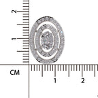 An oval cluster pendant or brooch with a central round clear gemstone surrounded by double rows of small clear stones in a silver-toned setting with gold-toned accents, shown next to a centimeter ruler for scale on a white background.