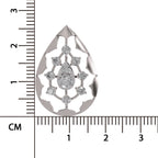 A teardrop-shaped silver pendant with a filigree cutout design and a central cluster of clear gemstones, shown next to a black ruler with centimeter markings to indicate scale.