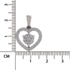 A silver heart-shaped pendant with a central round-cut clear gemstone and a border of small clear stones, shown next to a centimeter ruler for scale on a white background.