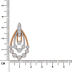 A teardrop-shaped diamond pendant in white gold or platinum with rose gold accents, shown next to a black ruler with centimeter markings to indicate its size.