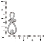 A silver-toned infinity-shaped pendant with pavé-set clear stones and a round center stone, shown next to a centimeter ruler for scale on a white background.