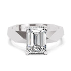 An emerald-cut diamond solitaire ring set in a polished silver-colored band, shown on a clean white background.