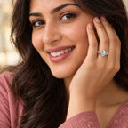 Smiling woman with long dark hair resting her hand against her cheek, wearing a white gold oval-cut 2.00 ct diamond engagement ring with a pavé diamond band
